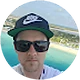 Person wearing a Nike cap and sunglasses with a beach background.